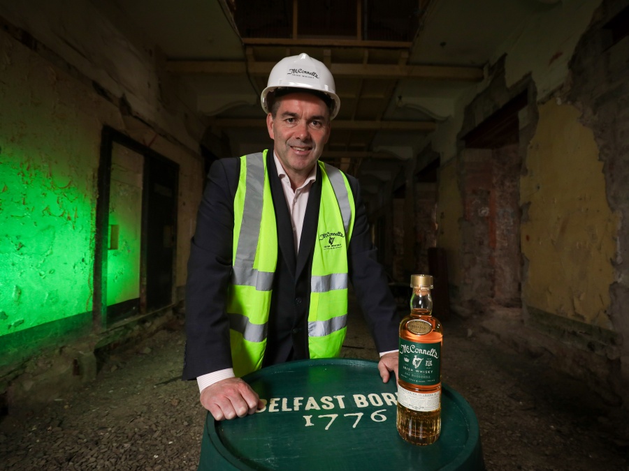 Belfast Distillery Company CEO John Kelly in Belfast next to a bottle of whiskey at a distillery construction site in Belfast
