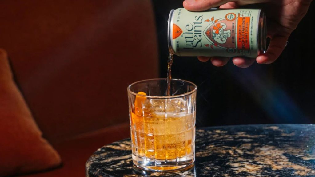 Canned orange drink being poured into glass on stone table, red and black background.